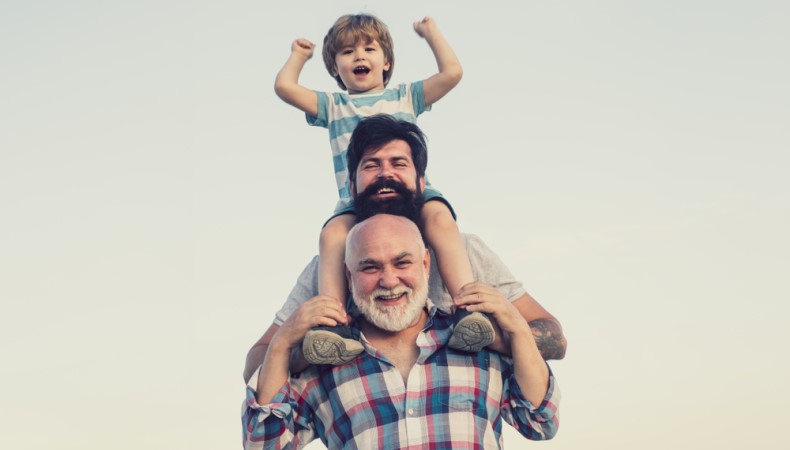 Three generations of men sitting on each other's shoulders